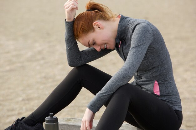 Photo femme sportive assise à l'extérieur et se détendre après l'entraînement