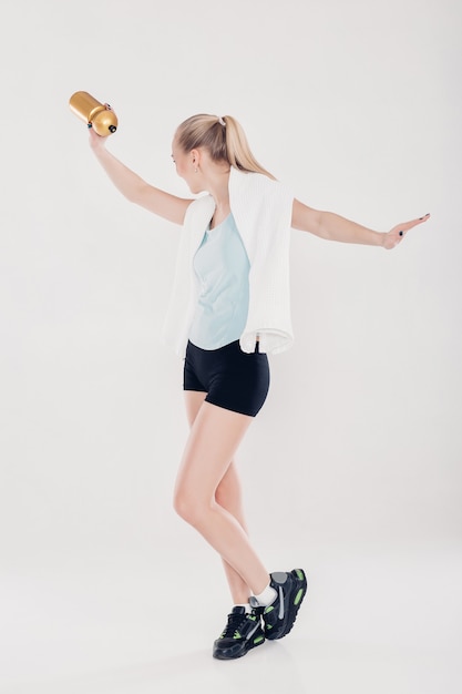 femme sportive en bonne santé en vêtements de fitness avec serviette de gym et bouteille d'eau. Lumière douce