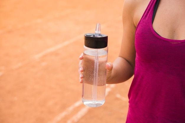 Photo femme sportive avec une bouteille d'eau sur la piste du stade