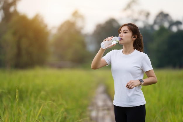 Femme sportive buvant de l'eau après avoir couru sur le terrain