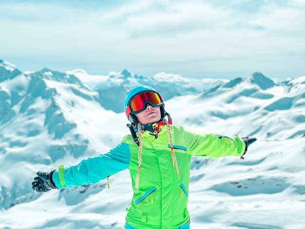 Une femme sportive en costume de ski et lunettes de soleil heureuse dans les montagnes