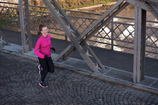 femme sportive courant sur le trottoir au jogging tôt le matin avec la scène du lever du soleil de la ville en arrière-plan