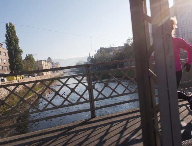 femme sportive courant sur le trottoir au jogging tôt le matin avec la scène du lever du soleil de la ville en arrière-plan