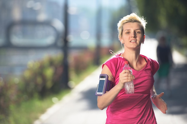 femme sportive courant sur le trottoir tôt le matin avec la scène du lever du soleil de la ville en arrière-plan