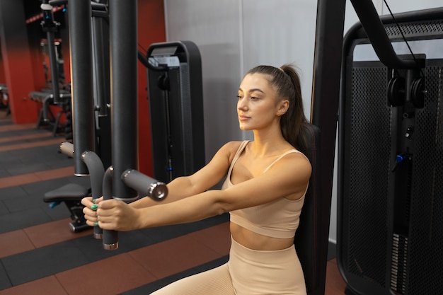 Femme sportive dans le gymnase sur le simulateur de papillon