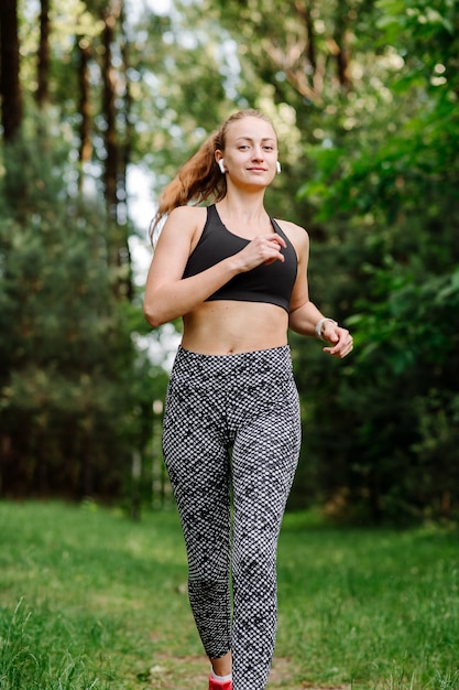 La femme sportive fait du jogging à l'extérieur dans le parc