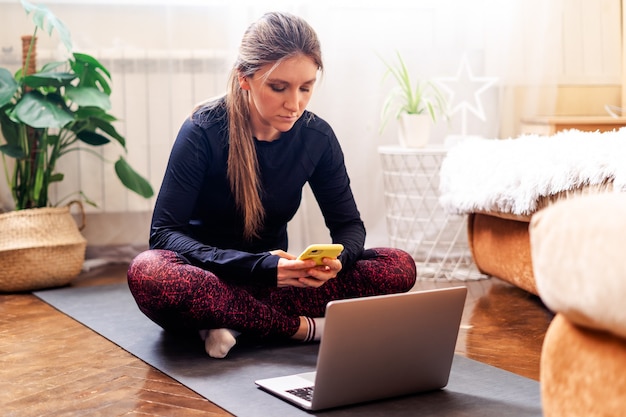 Une femme sportive à l'intérieur avec ordinateur portable et téléphone