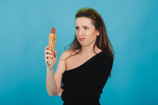 femme sportive en mangeant des hot-dogs sur fond bleu