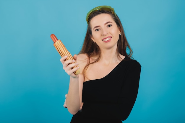 femme sportive en mangeant des hot-dogs sur fond bleu