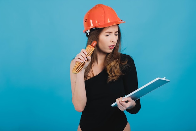 femme sportive en mangeant des hot-dogs sur fond bleu