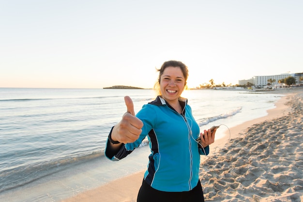 Femme sportive motivée faisant un geste de réussite après un entraînement urbain au bord de la mer.