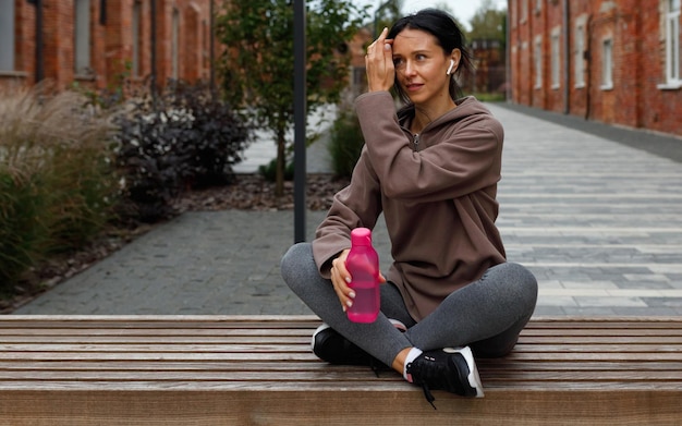 Femme sportive portant des écouteurs et tenant une bouteille d'eau