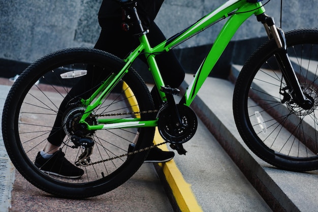 Une femme sportive porte un vélo sur les marches d'un passage souterrain