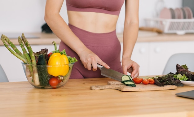 Femme sportive préparant une salade de légumes frais dans la cuisine concept de saine alimentation