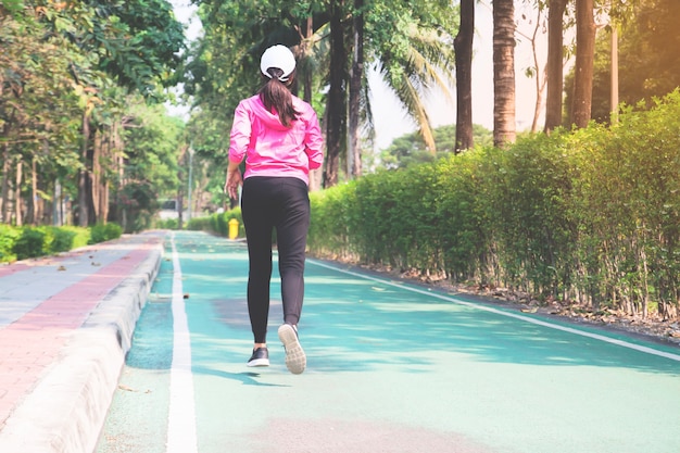 Femme sportive qui court sur la route dans le parc