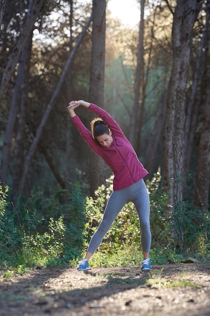 Femme sportive qui s'étend du corps sur le terrain avec un rayon de soleil et un espace de copie