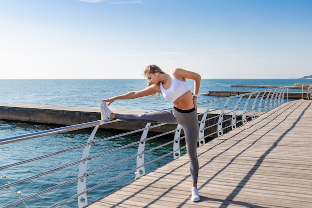 Femme sportive qui s'étend près de la mer.