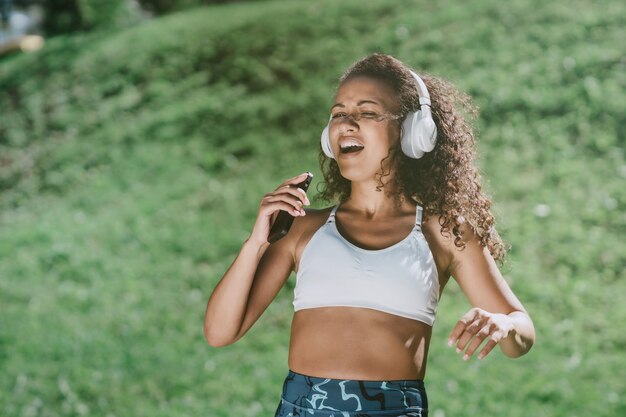 Femme sportive avec un smartphone dansant dans un parc de la ville