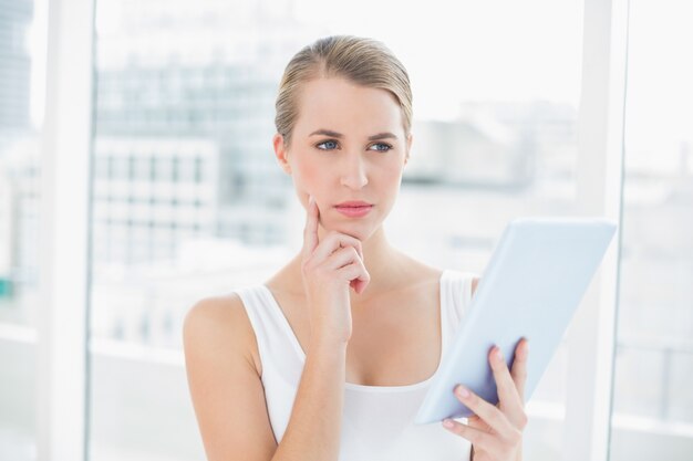 Femme sportive songeuse à l&#39;aide d&#39;une tablette