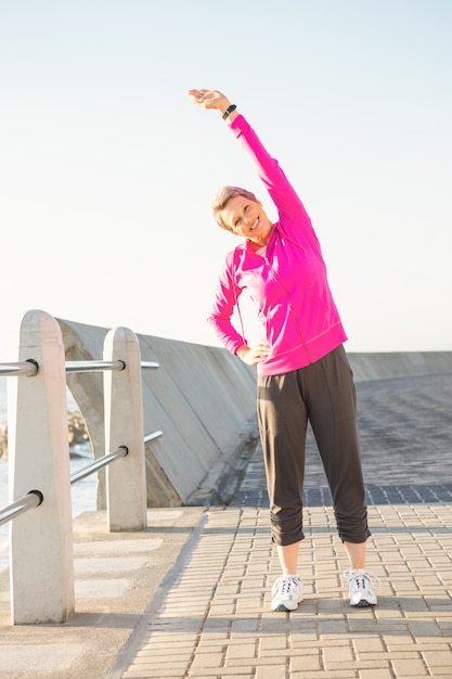 Femme sportive souriante qui s&#39;étend à la promenade