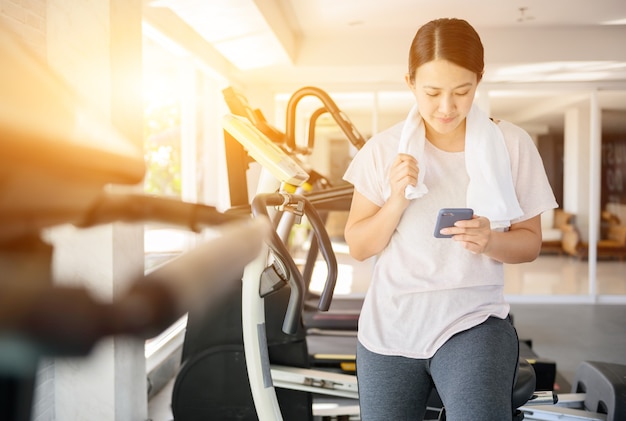 Femme sportive utilisant un téléphone portable lors de l'entraînement. Femme asiatique exerce seule et style de vie à la salle de fitness. Bien-être et santé.