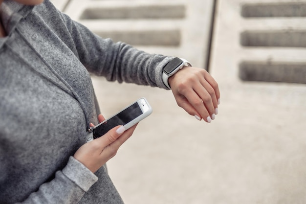 Une femme sportive utilise un smartphone avec un bracelet intelligent à l'extérieur Gadgets modernes Surveillance de la fréquence cardiaque