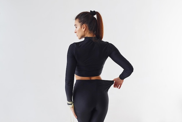 Femme sportive en vêtements noirs en studio sur fond blanc.