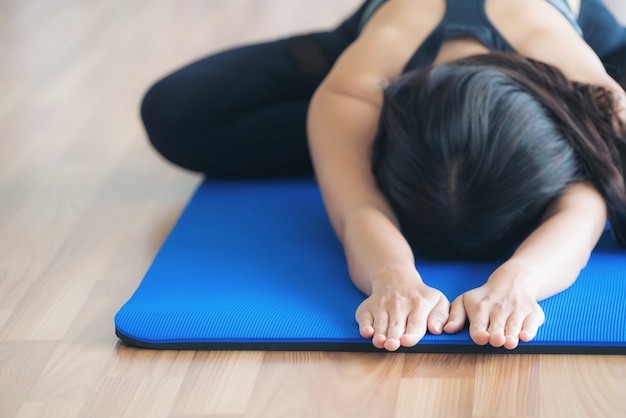 Femme en sportswear pratique la séance d&#39;entraînement de yoga qui s&#39;étend dans la salle de gym à l&#39;intérieur.