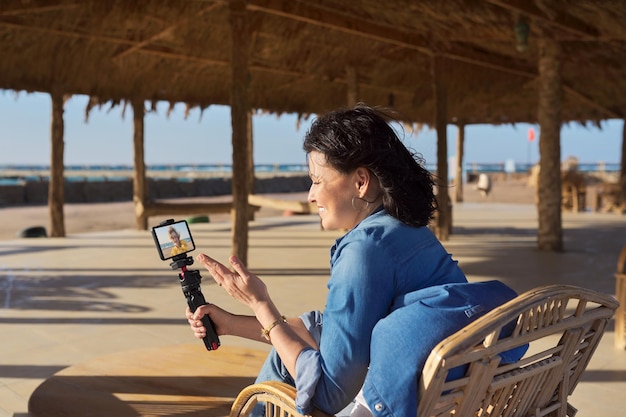 Femme à la station balnéaire parlant à son amie à l'aide d'un appel vidéo sur smartphone