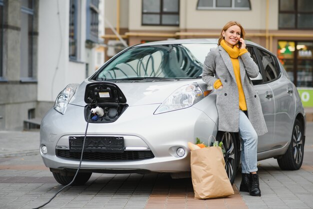 Photo femme sur la station de recharge de voitures électriques pendant la journée