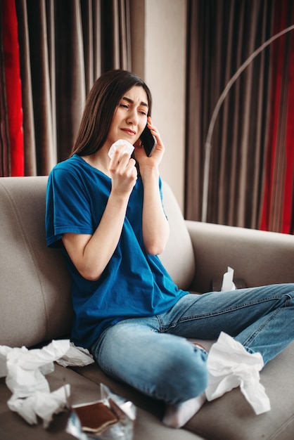 Femme stressée assise sur le canapé et mange du chocolat, concept de dépression féminine