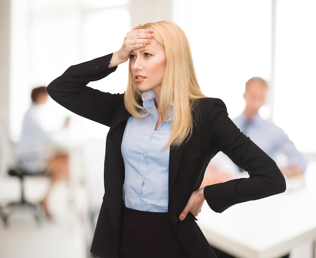 Photo femme stressée tenant sa tête avec la main au bureau