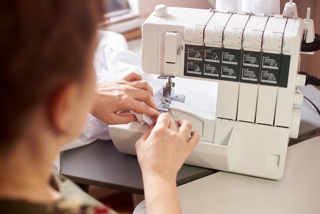 Femme en studio de couture couture avec surjeteuse surjeteuse Atelier de créateurs de mode Vue rapprochée de la machine à coudre