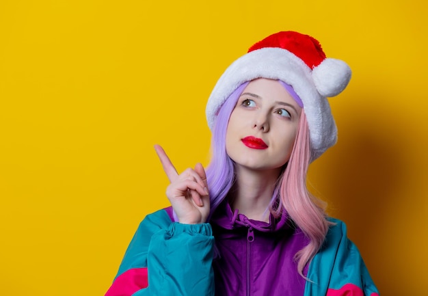 Femme de style en costume de sport des années 90 et chapeau de Noël sur fond jaune