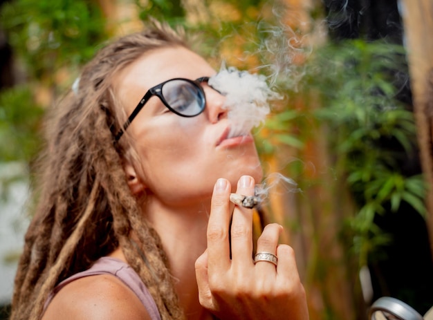 Photo femme de style hippie fumant des cigarettes avec de la marijuana médicale