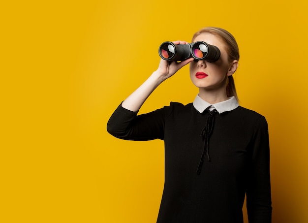 Femme de style en vêtements formels noirs avec jumelles