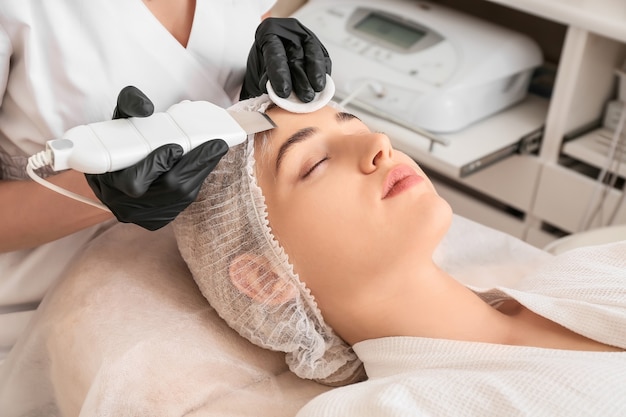 Femme subissant une procédure de peeling facial dans un salon de beauté