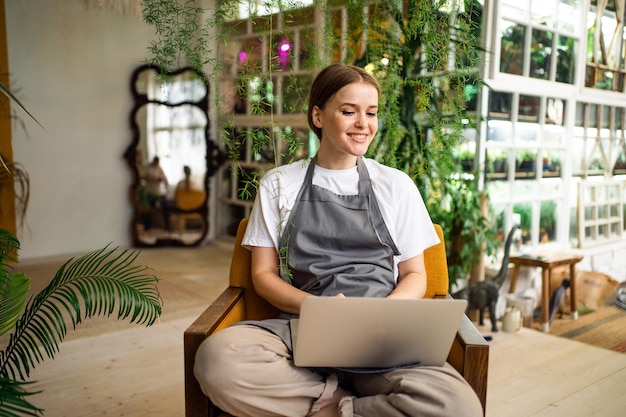 Une femme surfe sur Internet à la recherche d'informations sur les plantes Le fleuriste travaille dans son atelier