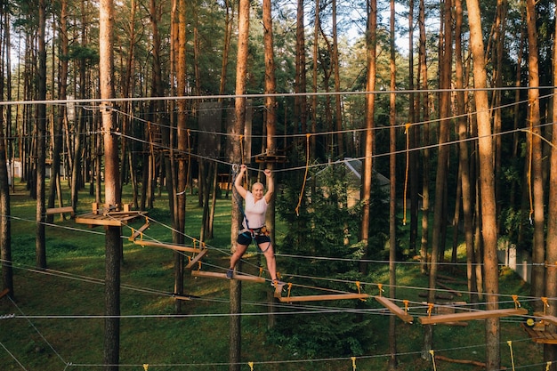 Une femme surmonte un obstacle dans une ville de cordes Une femme dans un parc de cordes en forêt