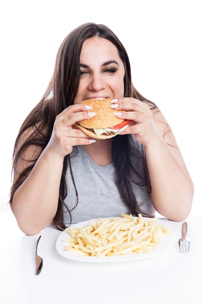 Femme en surpoids avec appétit mange avidement hamburger Obésité et restauration rapide Isolé sur fond blanc Vertical