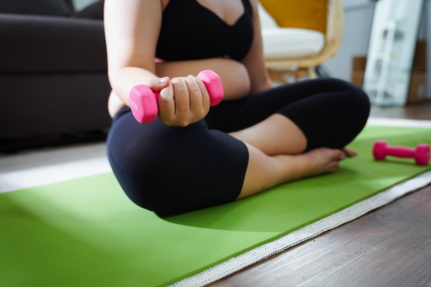 Femme en surpoids faisant de l'exercice pour perdre du poids avec des haltères dans des positions d'étirement à la maison dans le salon Enthousiaste grosse femme régime mode de vie sain concept