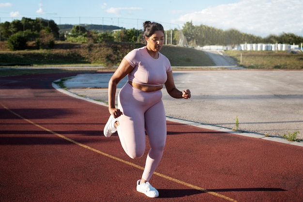 Photo femme en surpoids s'échauffant pour faire de l'exercice à l'extérieur