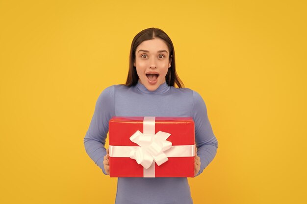 Femme surprise avec boîte cadeau rouge sur fond jaune anniversaire