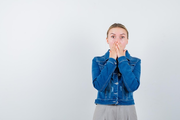 La femme surprise couvre sa bouche avec les mains sur fond blanc