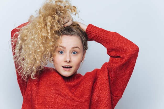 Une femme surprise émotionnellement à la caméra avec un look inattendu garde les cheveux en queue de cheval exprime la surprise isolée sur fond de studio blanc Son incroyable étonnement et choc