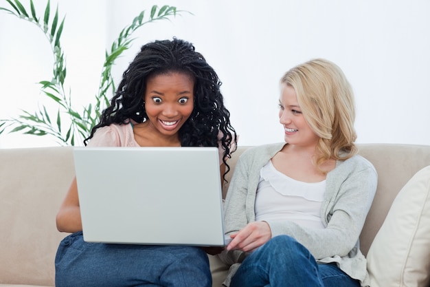 Une femme surprise en regardant un ordinateur portable avec son ami