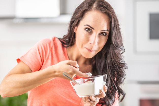 Une femme surprise en train de goûter de la crème fouettée dans un bol avec son doigt.