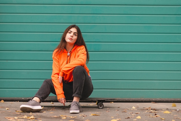 Femme en sweat à capuche se dresse avec un longboard