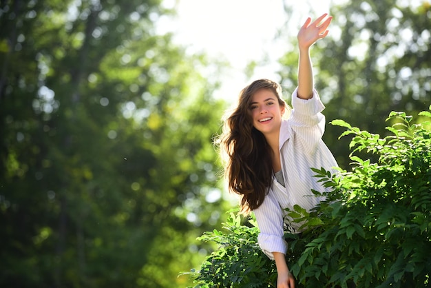 Femme sympathique disant bonjour sur fond de nature dans le parc d'été ou de printemps.