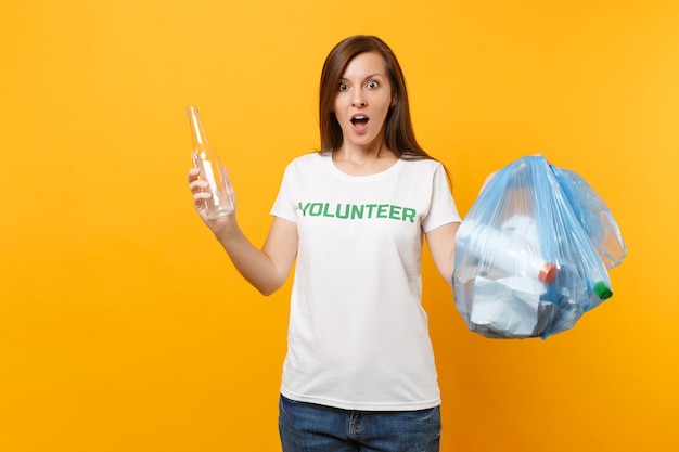 Femme en t-shirt bénévole, sac poubelle isolé sur fond jaune. Aide d'assistance gratuite volontaire, grâce de charité. Problème de pollution de l'environnement. Arrêtez le concept de protection de l'environnement des ordures ménagères.